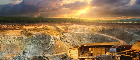 Yellow dump truck loading minerals copper, silver, gold, and other  at mining quarry.