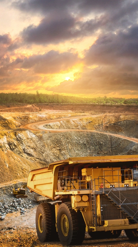 Yellow dump truck loading minerals copper, silver, gold, and other  at mining quarry.